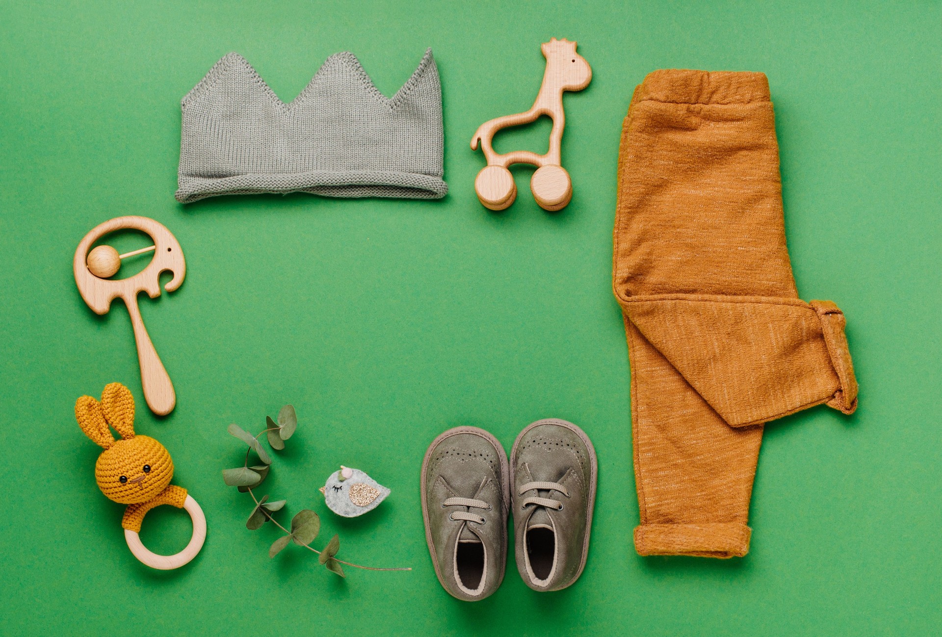 Wooden toys, clothes and shoes on green background