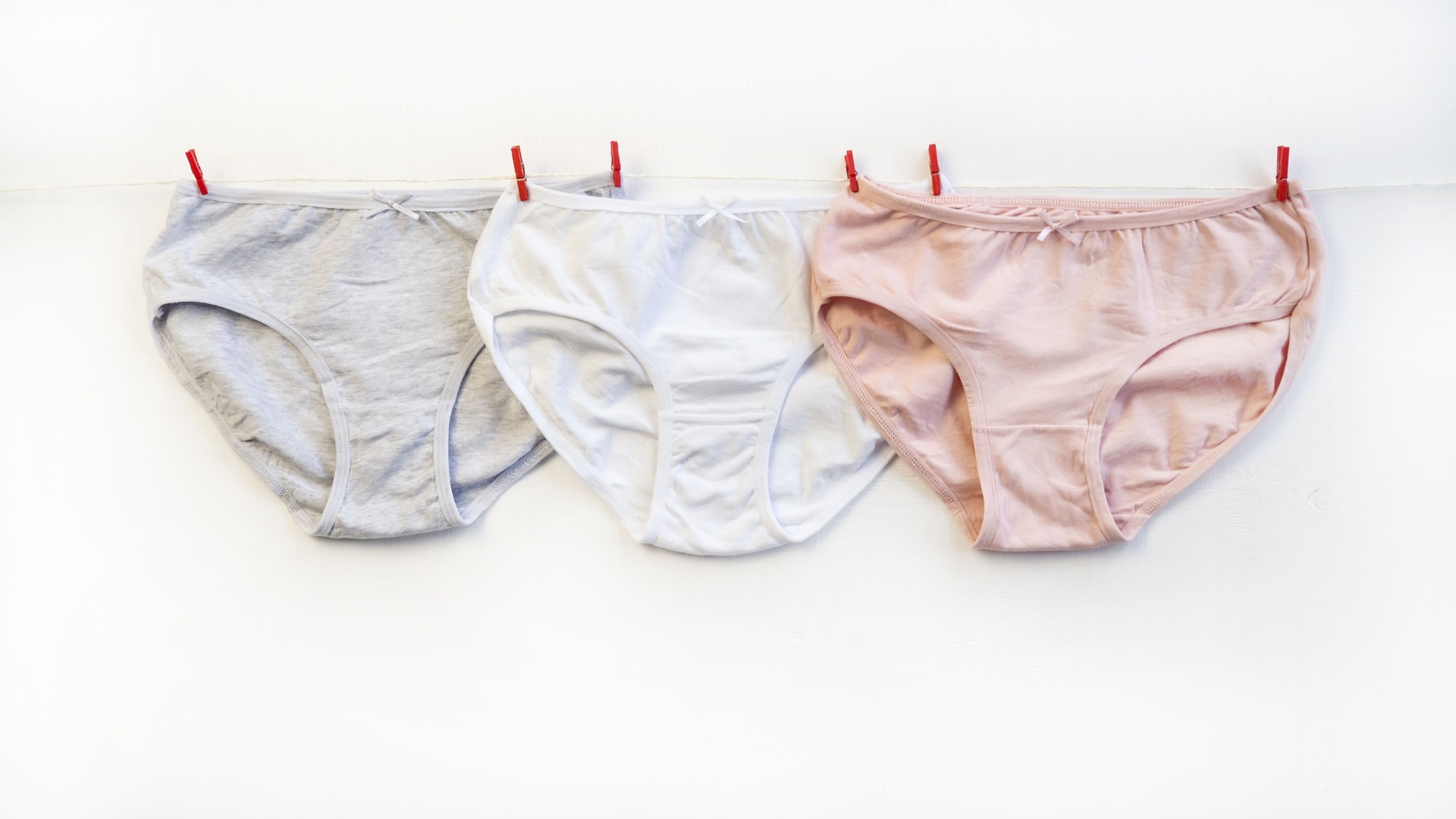 A set of panties hang on a rope. A set of colorful, cotton classic panties. Close-up. Underwear. Woman pants.